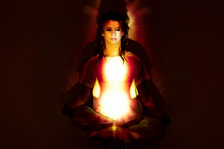 A woman in meditation surrounded by a radiant aura, symbolizing spiritual energy and enlightenment.