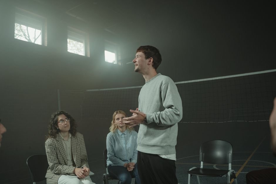 A group therapy session with three adults discussing mental health issues indoors.